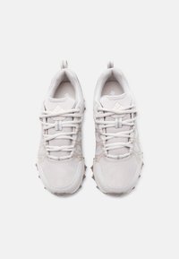 Ζευγάρι λευκών αθλητικών παπουτσιών με πλέγμα ύφασμα, παχιές κορδόνια και λαστιχένιες σόλες με ανάγλυφα μοτίβα, απεικονιζόμενα από ψηλά σε λευκό φόντο.