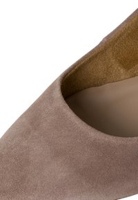 Měkká béžová semišová lodička s kulatým střihem a hladkým interiérem. Má klasický siluetu s minimálním designem.