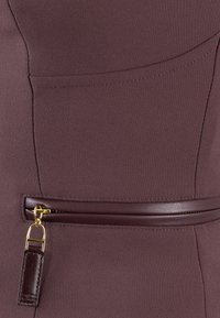 Tessuto di abito bordeaux con una texture liscia. Presenta una tasca orizzontale, un accento in pelle con una cerniera dorata e un piccolo dettaglio in pelle.