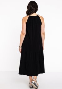 Zwarte halternek maxi jurk met een geraffineerde halslijn, gelaagde rok en een gladde textuur. Kenmerkt zich door een losse pasvorm en een enkellange stijl.