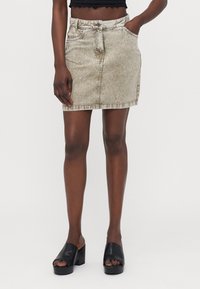 Light beige denim mini skirt with a fitted shape, front pockets, and a slightly distressed texture. Features a button closure and belt loops.
