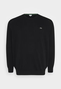 Sudadera negra hecha de una tela suave, con cuello redondo y mangas largas. Logo verde notable en el pecho y cuello interior en verde contrastante.