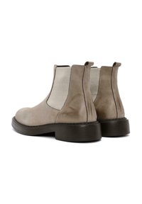 Botas Chelsea de cuero gris con paneles elásticos a los lados, punta redonda y suela negra gruesa. Se aprecian un brillo sutil y detalles cosidos.