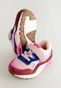 Kolorowe buty sportowe z mieszanką różowych, fioletowych i burgundowych materiałów, z rzepem, teksturowaną podeszwą i kontrastującymi akcentami.