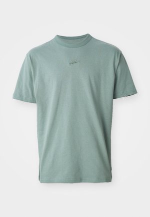 T-shirt in cotone verde con maniche corte, colletto a girocollo rib ribattuto e logo Nike ricamato sul petto. Tessuto liscio e vestibilità rilassata.