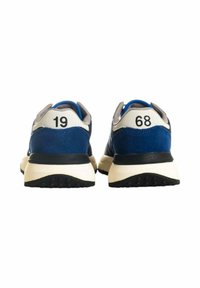 Sneakers blu in suede con suole nere, caratterizzati da accenti bianchi e grigi. Numeri "19" e "68" mostrati sul tallone. Design atletico classico.