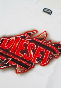 T-shirt bianco in stile spray con logo e testo "For Successful" visibile sotto i bordi strappati in rosso e nero.