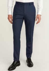 Granatowe, dopasowane spodnie wykonane z tkaniny o delikatnej teksturze, z zapięciem na guzik i bocznymi kieszeniami, w połączeniu z czarnymi eleganckimi butami.