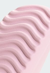 Surface rose douce avec des crêtes ondulées courbées et espacées uniformément, avec un motif texturé subtil.