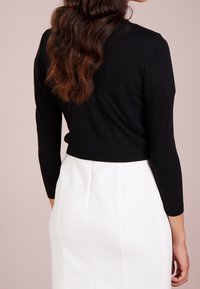 Czarny krótki sweter z długim rękawem, o dzianinowej strukturze, zestawiony z białą spódnicą o fakturowanej powierzchni, z panelowymi detalami i dopasowanym krojem.
