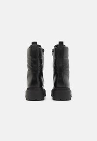 Botas de tornozelo em couro preto com um design almofadado, acabamento texturizado, fechos de correr laterais duplos e uma sola de borracha grossa.