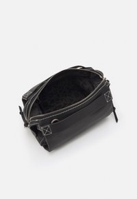 Svart läderväska med texturerad yta, dragkedja och vita sömmar. Insidan har ett mönstrat svart foder. Kompakt och rektangulär form.