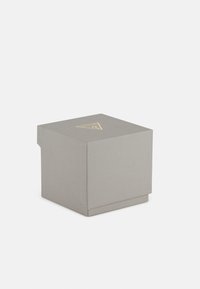 Szary pudełko teksturowane z pokrywką, z złotym logo na górze. Kompaktowy kwadratowy design o uporządkowanym kształcie i subtelnych detalach.