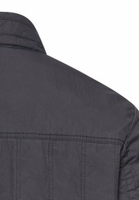 Donkere grijze jas achterkant met zichtbare stiklijnen en een opstaande kraag, waarbij het bovenste deel van de schouders en de rug zichtbaar zijn.