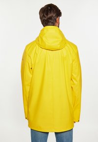 Geel waterdichte jas met capuchon, gladde textuur, lange mouwen en drukknoopsluiting bij de manchetten. Heeft een rechte snit en een lichtgewicht ontwerp.