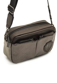 Bolso cruzado de textura marrón con dos compartimentos con cremallera, correa ajustable y acento de logo en la parte frontal.