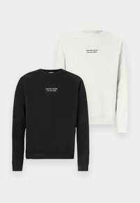 Kaksi pyöreäkauluksista collegepaitaa pinottuna. Toinen on musta valkoisella logolla; toinen vaaleanharmaa, jossa samanlainen logo. Puuvillamateriaalia, pitkät hihat.