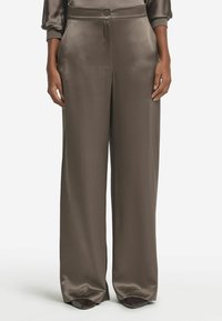 Hög midja, vida byxor i ett slätt, mörkt taupe-satinmaterial. Har en framknäppning och sidofickor.