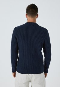 Marineblaue gerippte Strickjacke mit langen Ärmeln und Rundhalsausschnitt, die ein strukturiertes Strickmuster und eine lockere Passform aufweist.