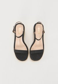 Musthave musta kangast sandaalid slingback disainiga ja kahe laia rihmaga. Beez sisetald, millel on kuldne brändi logo ja tekstureeritud tald.