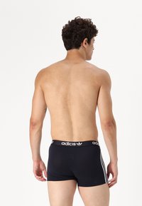 Sorte boksershorts med en kontrastfarget hvit midjebånd som har "adidas"-logoen. Sidelinjer i hvitt. Glatt, stretchy stoff.