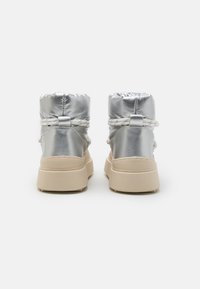 Botas de tobillo acolchadas plateadas con parte superior acolchada, cordón elástico y suela gruesa beige. Presentan un material suave y reflectante.