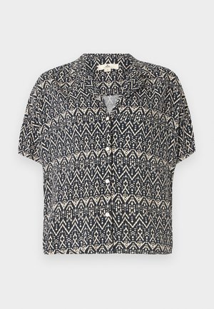 Trumpo rankovėmis, mygtukais užsegamas marškinys tamsiai mėlynos spalvos, su geometriniu kreminiu raštu. Lengvas audinys, laisvas kirpimas ir apykaklė.