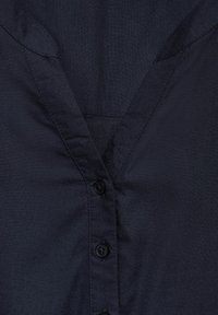 Navyblauwe overhemd met knopen en een V-hals, met een gladde stoftextuur en zichtbare stiksels langs de naden.