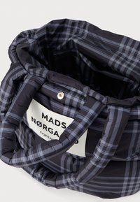 Black plaid tote bag with a soft, padded texture, featuring two handles and a white label that reads "MADS NØRGAARD COPENHAGEN."