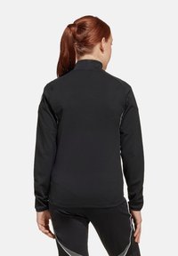 Zwarte sportieve jas van gladde, rekbare stof, met een hoge kraag, lange mouwen en reflecterende accenten op de schouders.
