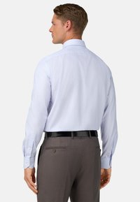 Camisa de vestir a rayas azul claro con mangas largas, puños de botón y un cuello clásico, combinada con pantalones grises y un cinturón negro.
