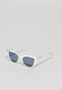 Ochelari de soare din plastic transparent cu lentile de culoare albastru închis, formă de ochi de pisică și accente argintii pe brațe.