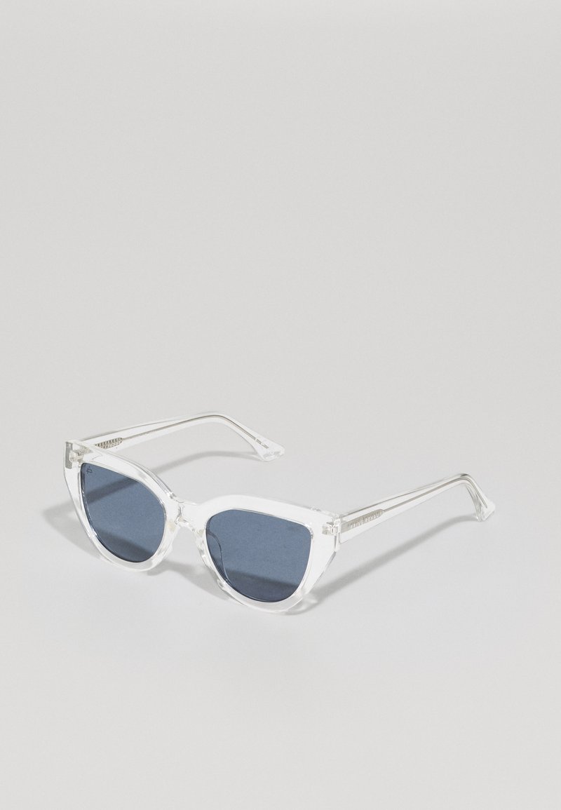 Ochelari de soare din plastic transparent cu lentile de culoare albastru închis, formă de ochi de pisică și accente argintii pe brațe.
