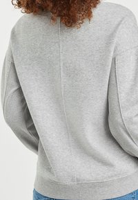 Grå sweatshirt med en struktureret overflade, der har en afslappet pasform, brede ærmer og ribbede kanter, som viser et enkelt design.