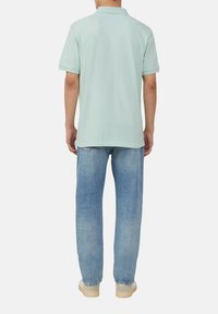Lichtgroene polo met korte mouwen en een kraag, gecombineerd met lichtblauwe, relaxed-fit jeans. Eenvoudig ontwerp zonder patronen.