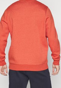 Sudadera de mezcla de algodón en naranja brillante, con un cuello redondo de canalé, mangas largas y una tela sólida y texturada con un corte holgado.