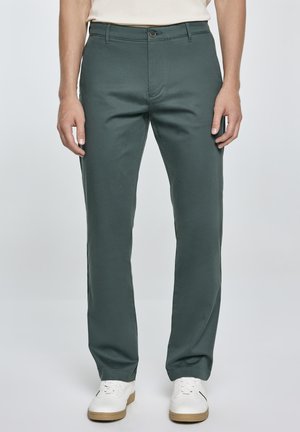 Groene katoenen broek in een rechte pasvorm, met een knoopsluiting aan de voorkant en zijzakken, gecombineerd met witte sneakers.