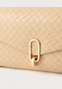 Beige geweven leren clutch met een gladde textuur. Voorzien van een goudkleurige metalen sluiting in ovale vorm. Simpel en elegant plat ontwerp.