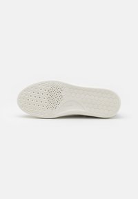 Suela de zapato de goma blanca con un patrón de panal, que presenta recortes circulares y un diseño texturizado cerca del talón para proporcionar agarre y flexibilidad.