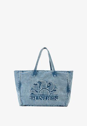Bolso de lona de mezclilla en azul claro con logo de "SUNDEK" en relieve y diseño floral. Cuenta con dos asas resistentes y un compartimento principal espacioso.
