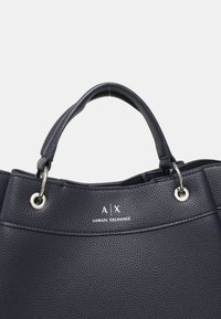 Borsa a tracolla in faux leather testurizzato di colore blu navy con due manici, accessori in argento e logo impresso nella parte superiore. Presenta un design arrotondato.