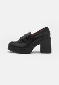 Mocasines de plataforma de cuero negro con puntera redonda, detalle de correa ancha y tacón cuadrado; textura suave y diseño minimalista.