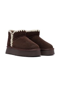 Bruine suede enkellaarzen met een dikke zool, geaccentueerd met witte zigzagstiksels en een getextureerde binnenkant voor warmte en comfort.