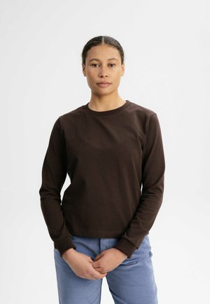 Brown long-sleeve cotton shirt with a crew neckline, paired with light blue corduroy pants. Simple design, fitted silhouette, and ribbed cuffs.