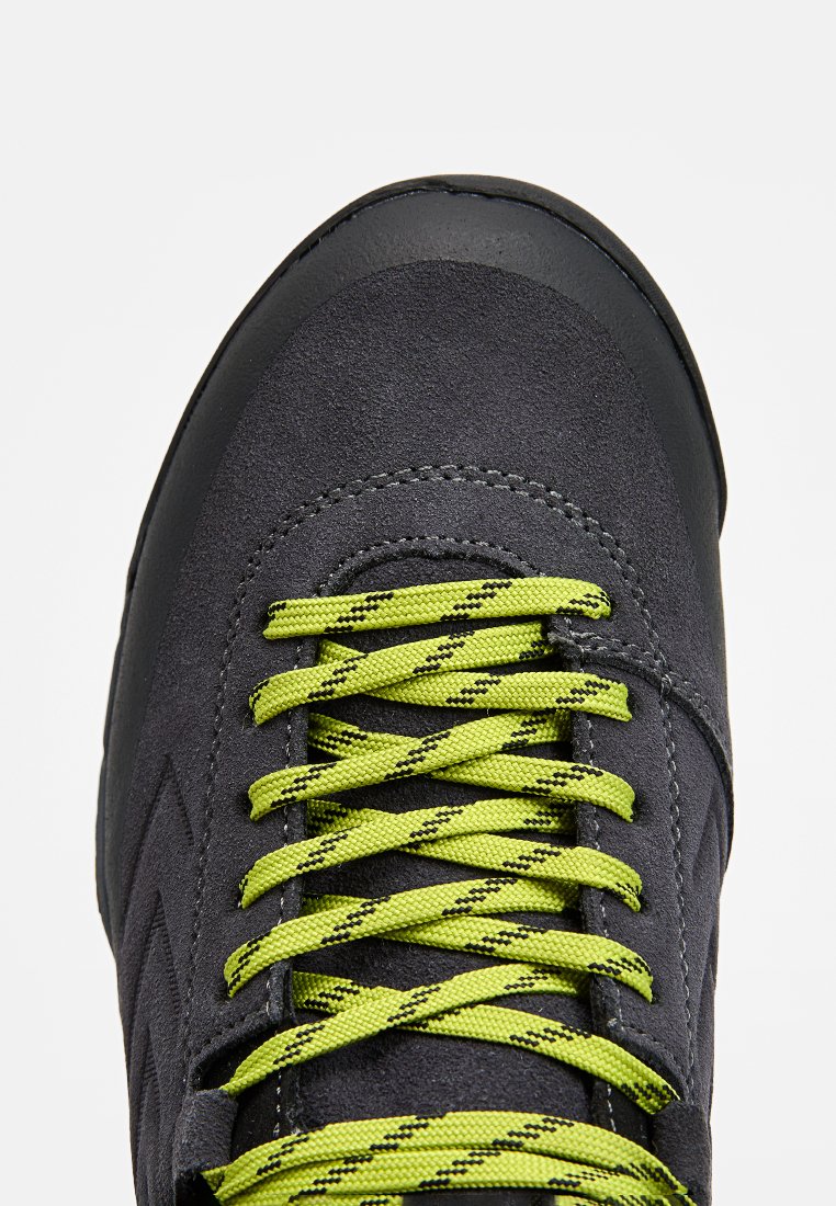 Szare zamszowe buty z czarnym gumowym noskiem, z jasnoniebieskimi sznurowadłami ozdobionymi wzorem. Gładka tekstura i wypukłe detale szwu.