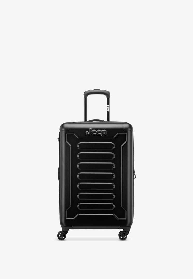 Valigia rigida nera con design a scanalature, manico retrattile e quattro ruote per la mobilità. Logo del marchio ben visibile sulla parte frontale.