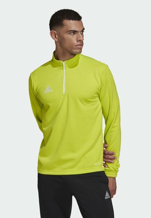 Lime green athletic quarter-zip pullover, long sleeves, smooth texture, white logo on chest, black pants with similar branding.