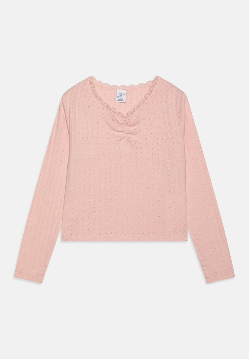Light pink long-sleeve top with a V-neck, gathered center detail, and scalloped lace trim. Made from textured fabric with small patterns.