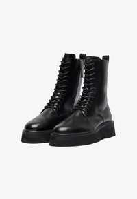 Botine negre din piele cu vârfuri rotunde, șireturi în față și fermoar pe lateral. Dispune de tălpi groase din cauciuc negru și o textură netedă, lucioasă.