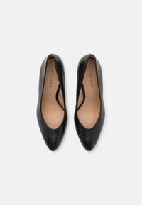 Black leather high heel shoes with a pointed toe and a low-cut design. Smooth texture with a tan insole, featuring subtle branding inside.